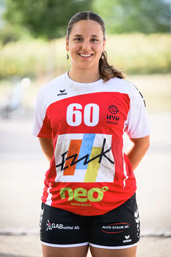 Female athlete in a red and white jersey with the number 60, smiling outdoors.