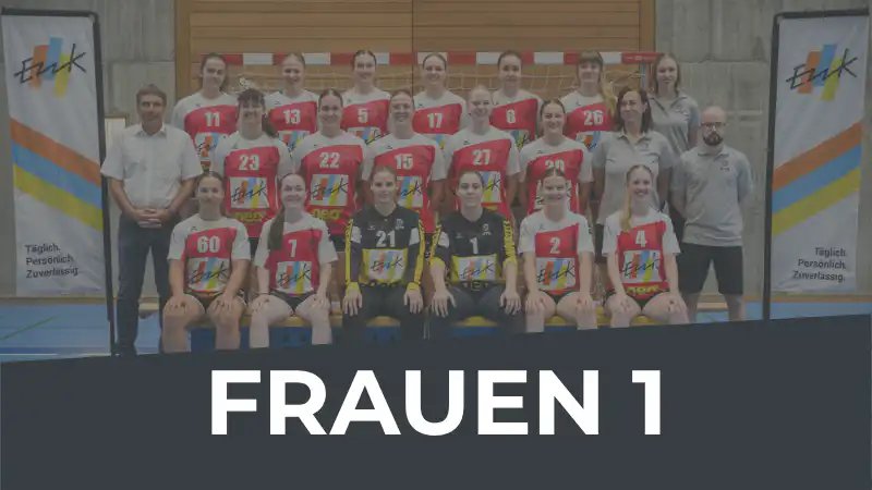 Group photo of the Frauen 1 women's volleyball team posing in a gym, players in red and white jerseys with coaches on the sides; a large dark banner across the bottom reads "FRAUEN 1".