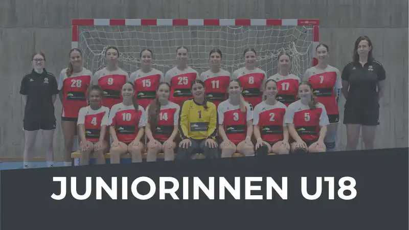 Group photo of a junior girls' handball team (U18) in a gym, wearing red and white jerseys with two coaches at the ends; a goalkeeper in yellow sits in the center.
